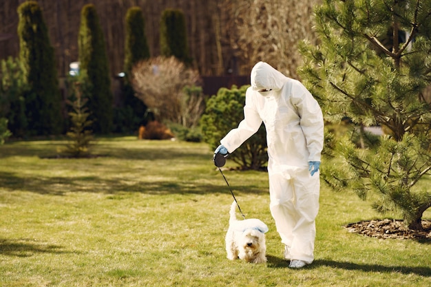 Frau in einem Schutzanzug, der mit einem Hund geht