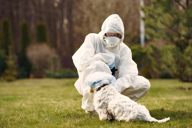 Frau in einem Schutzanzug, der mit einem Hund geht