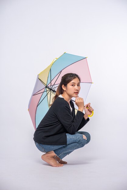 Frau in einem schwarzen Hemd, das sitzt und einen Regenschirm ausbreitet