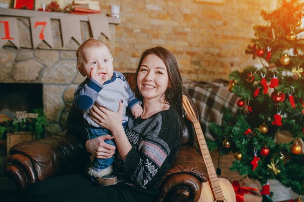 Frau in einem Sessel sitzend mit ihrem Baby und einer Gitarre daneben