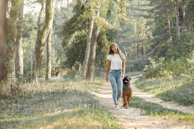 Frau in einem Sommerwald, der mit Hund spielt