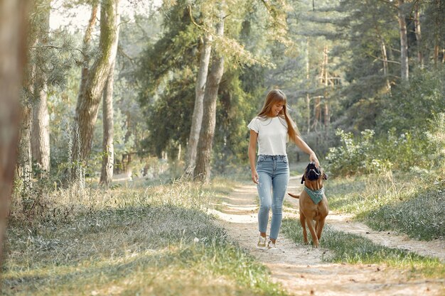 Frau in einem Sommerwald, der mit Hund spielt