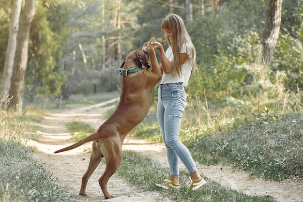 Frau in einem Sommerwald, der mit Hund spielt