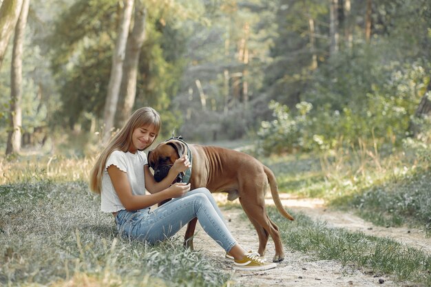 Frau in einem Sommerwald, der mit Hund spielt