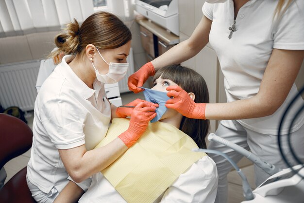 Frau in einem Zahnarztstuhl. Mädchen wird von einem Zahnarzt untersucht. Zahnärzte behandeln die Zähne eines Mädchens
