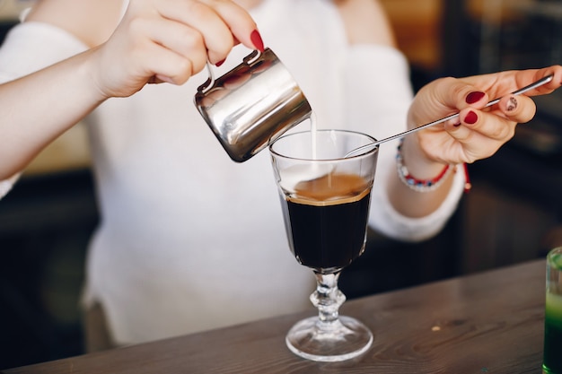 Frau in einer auslaufenden Milch der weißen Strickjacke in Kaffeenachtisch