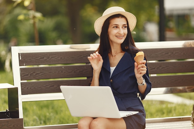 Frau in einer Frühlingsstadt. Dame mit einem Laptop. Mädchen sitzt auf einer Bank.