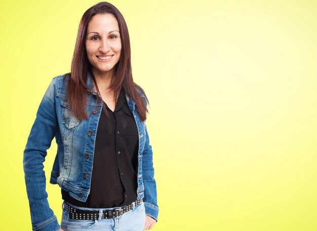 Frau in einer Jeansjacke in einem gelben Hintergrund lächelnd