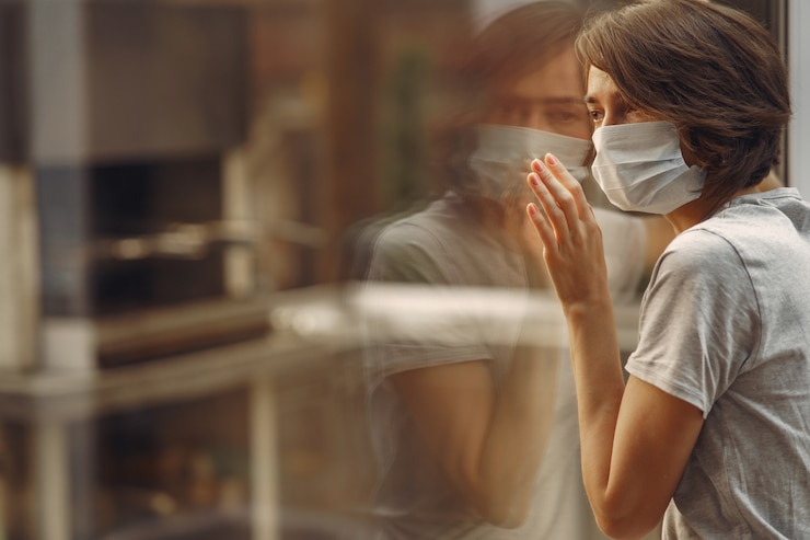 Kostenlose Foto frau in einer maske steht am fenster