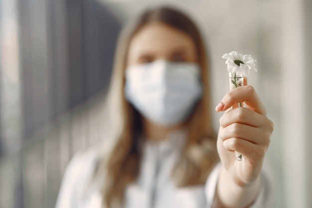 Frau in einer Maske und Uniform, die eine Blume in ihren Händen hält