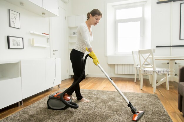 Frau in Freizeitkleidung Staubsauger den Teppich