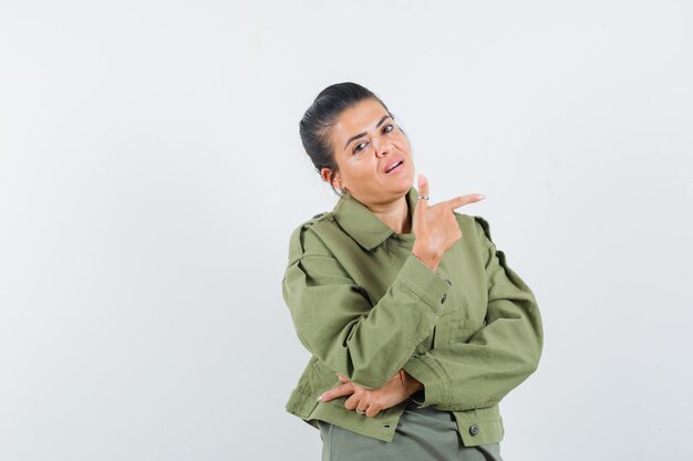 Frau in Jacke, T-Shirt zeigt nach rechts und sieht selbstbewusst aus