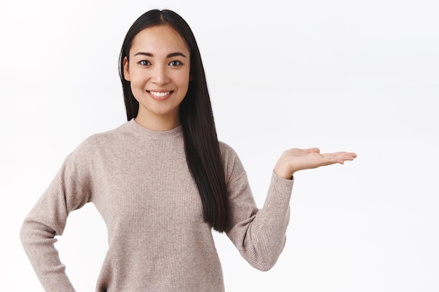 Frau in lässigem Pullover, Produkt oder Banner vorstellen, Unternehmenswerbung präsentieren, freudig und höflich lächeln