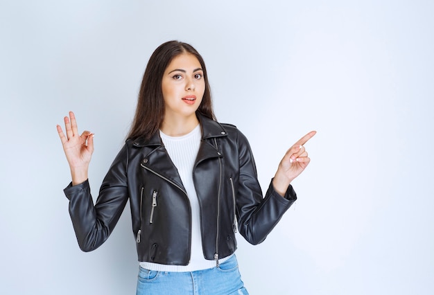 Frau in Lederjacke, die rechts etwas zeigt.