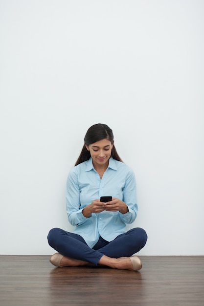 Frau in Lotus Position mit Smartphone