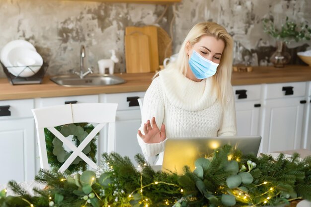 Frau in medizinischer Maske, Weihnachtsbaum-Bokeh im Hintergrund.