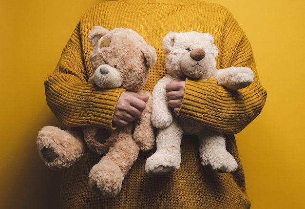 Frau in orangefarbenem strickpullover umarmt süßen braunen teddybären. das konzept der einsamkeit und traurigkeit, depression