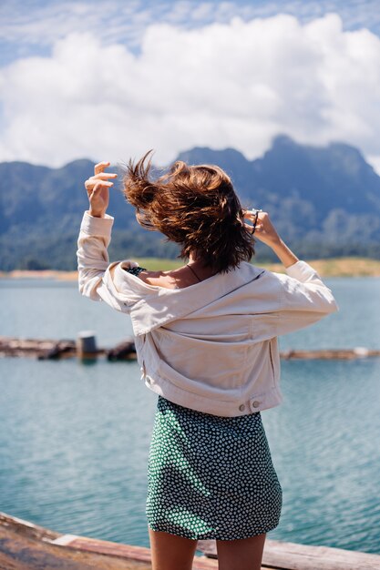 Frau in Sommerkleid und Jacke Touristenreise in Thailand, Khao Sok Nationalpark, herrliche Aussicht auf Boote und See.