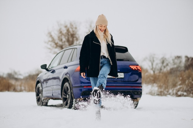 Kostenloses Foto frau in winterkleidung, die an ihrem auto steht