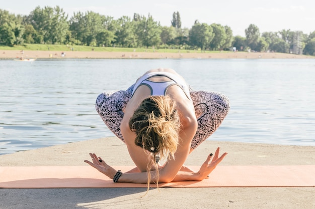 Frau in Yoga-Pose am Fluss