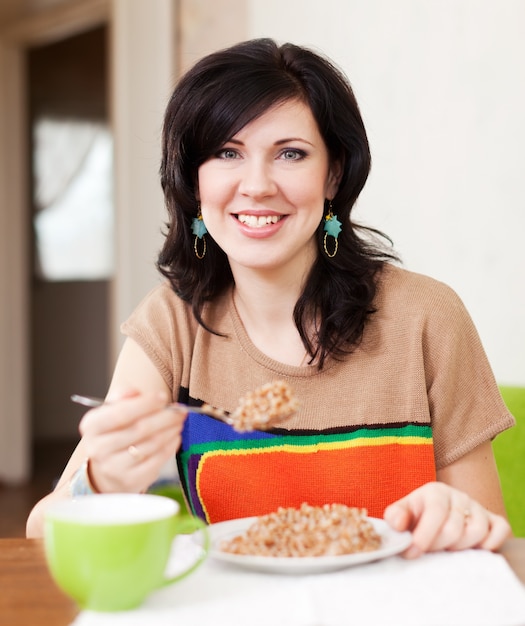 Frau isst Müsli zu Hause