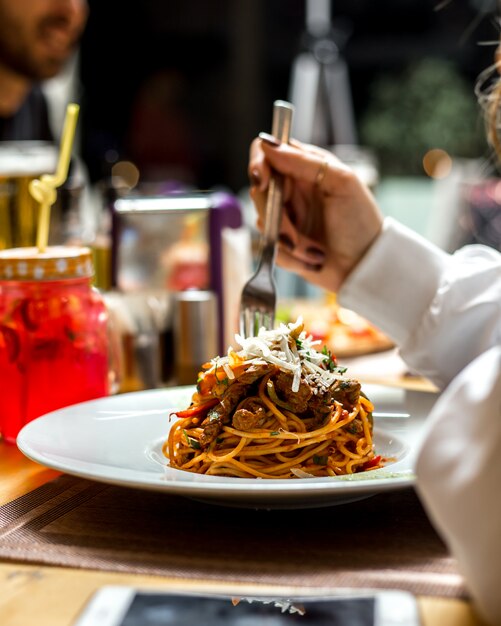 Frau isst Nudel-Spaghetti mit Fleischgrün-Parmesan-Seitenansicht
