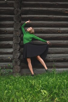 Frau junger erwachsener schön in einem grünen pullover an der blockwand des hauses