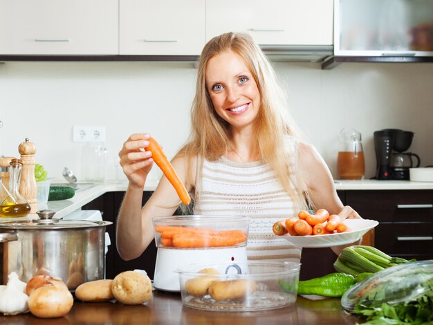 Frau kocht frisches Gemüse mit Dampfer
