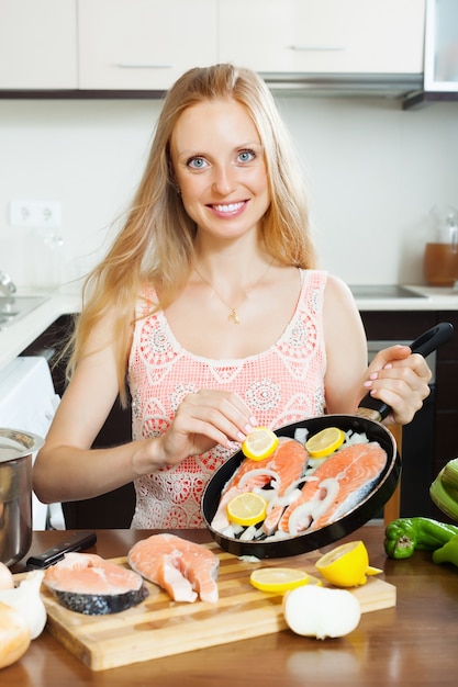 Frau kocht Lachs mit Zitrone