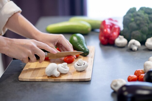 Frau kocht Mittagessen und schneidet Gemüse