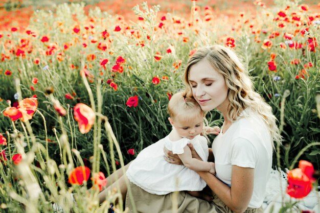 Frau kuschelt sich an ihr Baby auf dem Mohnblumenfeld
