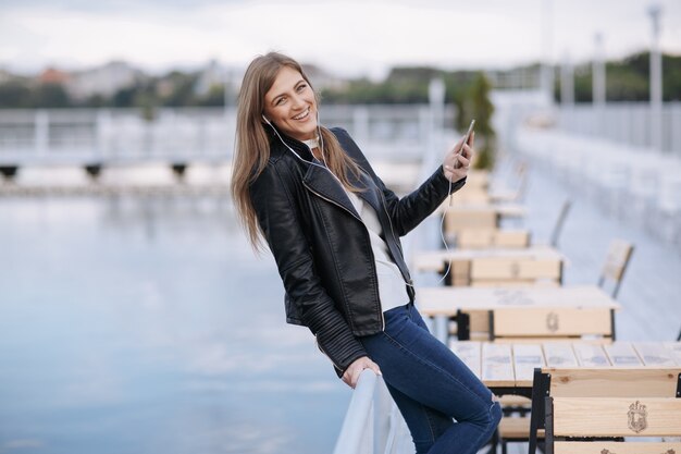 Frau lachend stützte sich auf ein Geländer mit einem Handy in der Hand