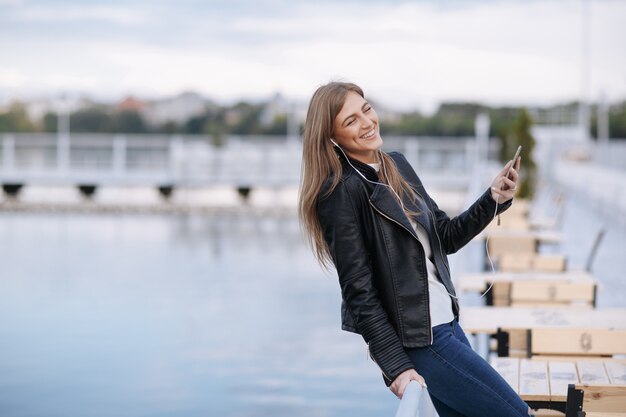 Frau lachend stützte sich auf ein Geländer mit einem Handy in der Hand