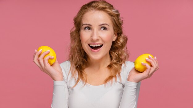 Frau lacht, die Zitronen hält