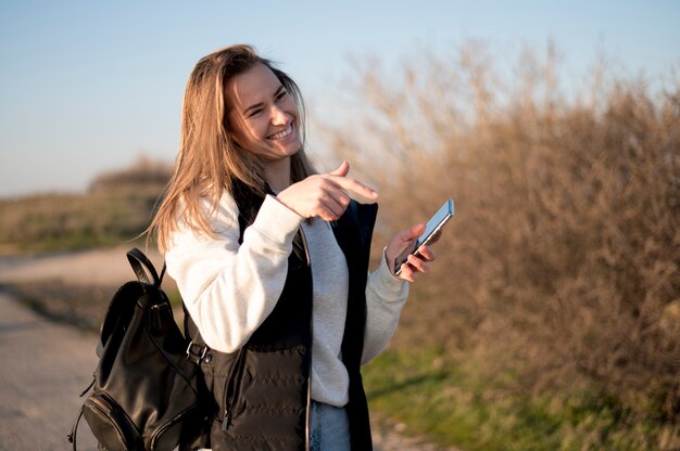 Frau lacht und zeigt auf ihr Telefon