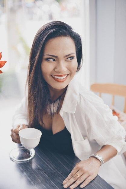 Frau lächelnd mit einer Tasse Kaffee