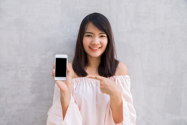 Frau lächelnd zeigt auf ihrem mobiltelefon