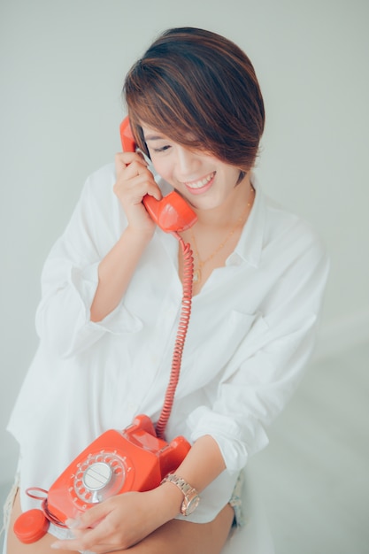 Frau lächelt, während auf einem roten Telefon sprechen