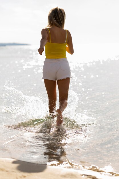 Frau läuft durch Wasser am Strand