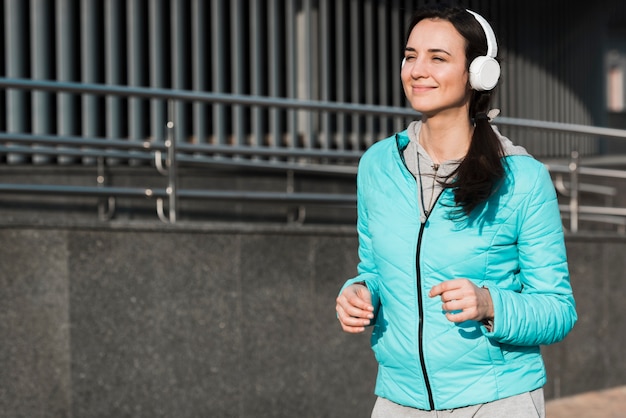 Frau läuft, während Musik durch Kopfhörer hört