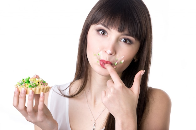 Frau leckt ihre Finger beim Essen Kuchen