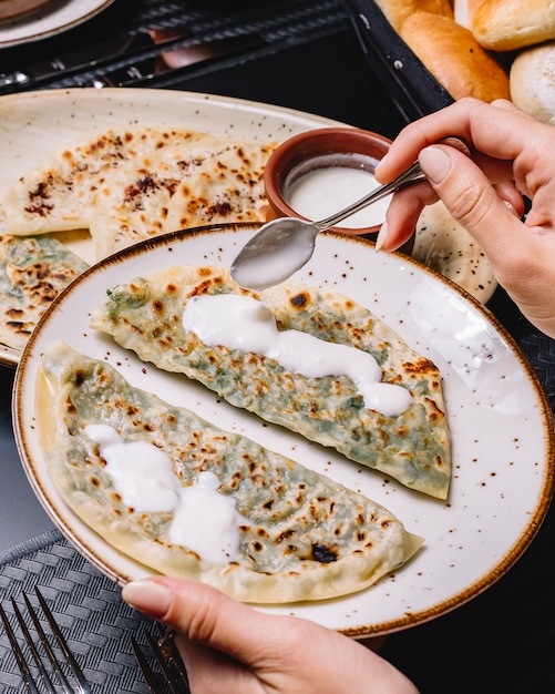 Kostenloses Foto frau legt joghurt auf aserbaidschanischen gutab mit kräutern