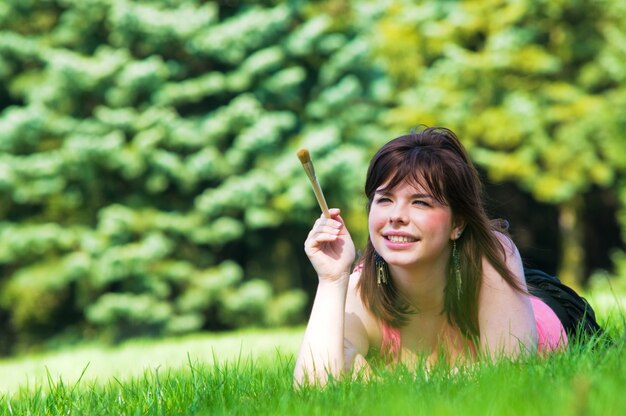Frau liegt auf dem Rasen mit einem Pinsel