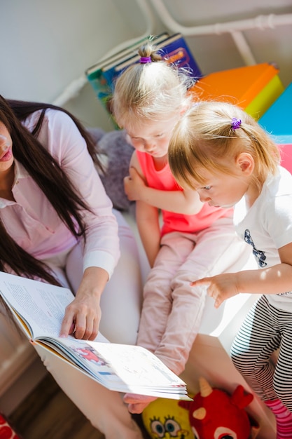 Frau liest Buch zu Kindern