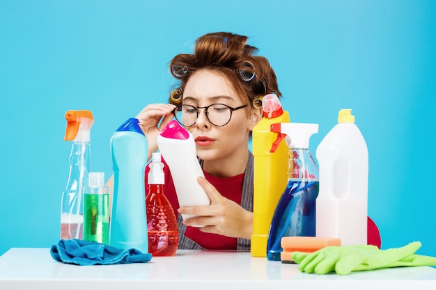 Frau liest Details auf Flasche während der Hausarbeit, sie sieht müde aus