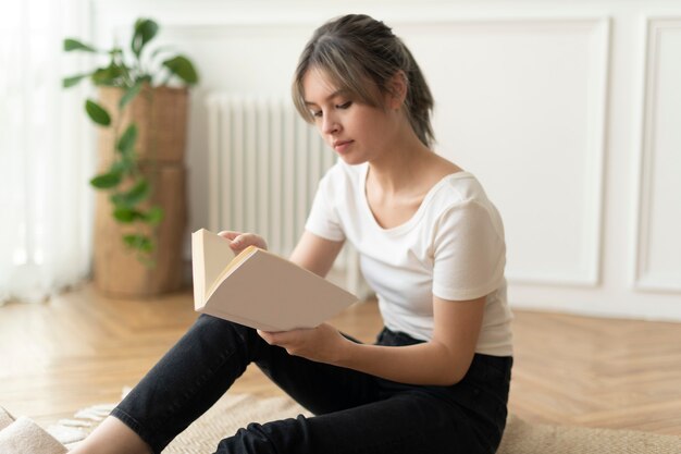 Frau liest ein Buch auf dem Boden sitzend