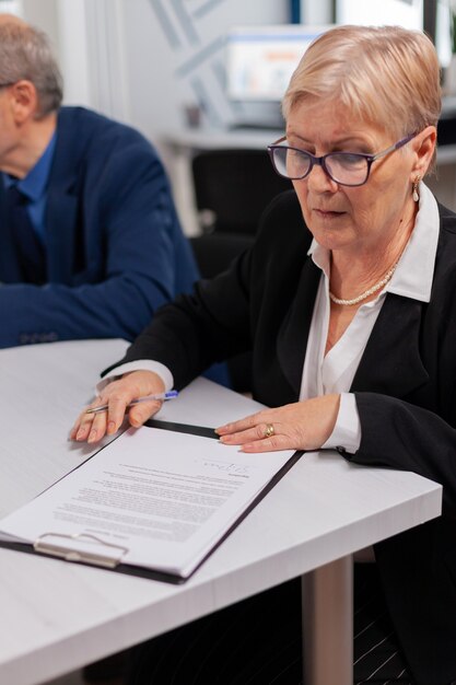 Frau liest Finanzdokumente im Konferenzraum, bevor sie sie unterschreibt