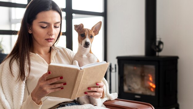 Frau liest, während sie ihren Hund hält