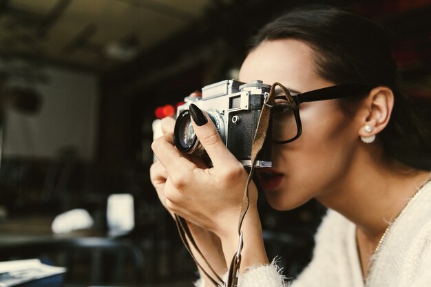 Frau macht ein Foto auf dem Retro- photocamera, das im Café sitzt