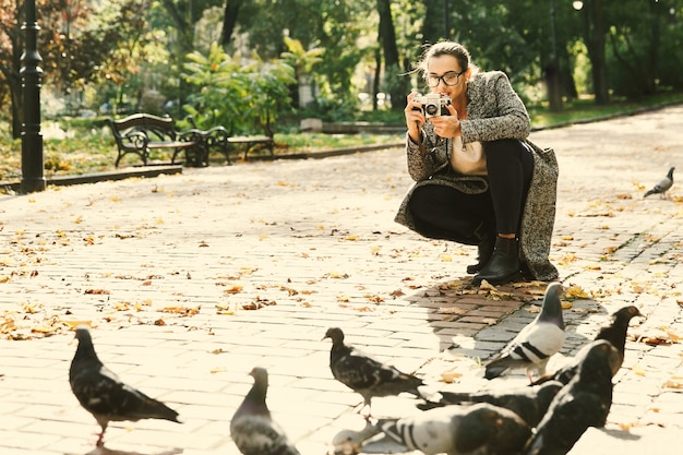 Frau macht ein Foto von den Tauben, die im Park stehen